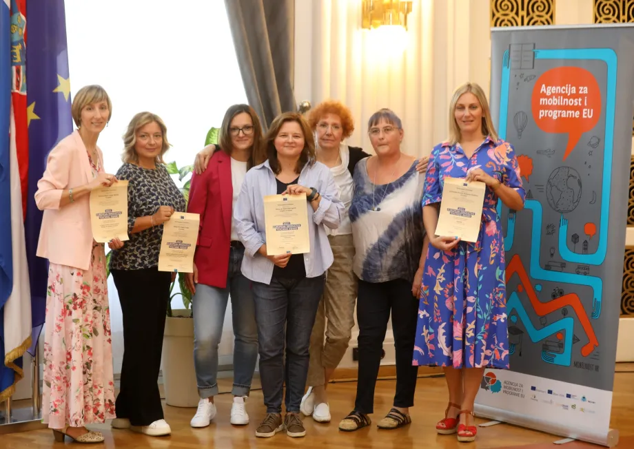 Dobitnice Europske nagrade za inovativno proučavanje poziraju skupa sa svojim priznanjima. U pozadini se nalazi banner Agencije za mobilnost i programe EU te zastave RH i EU.