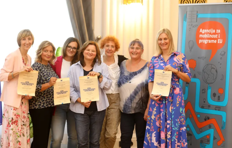 Dobitnice Europske nagrade za inovativno proučavanje poziraju skupa sa svojim priznanjima. U pozadini se nalazi banner Agencije za mobilnost i programe EU te zastave RH i EU.