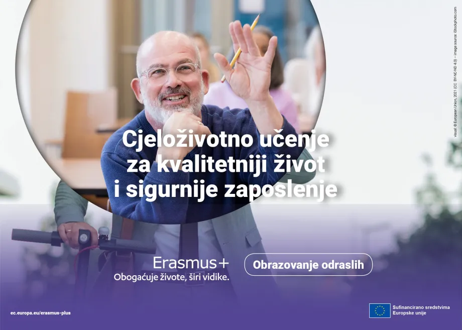 Muškarac srednjih godina sjedi u učionici, jednu ruku drži u zraku i u toj ruci drži olovku
