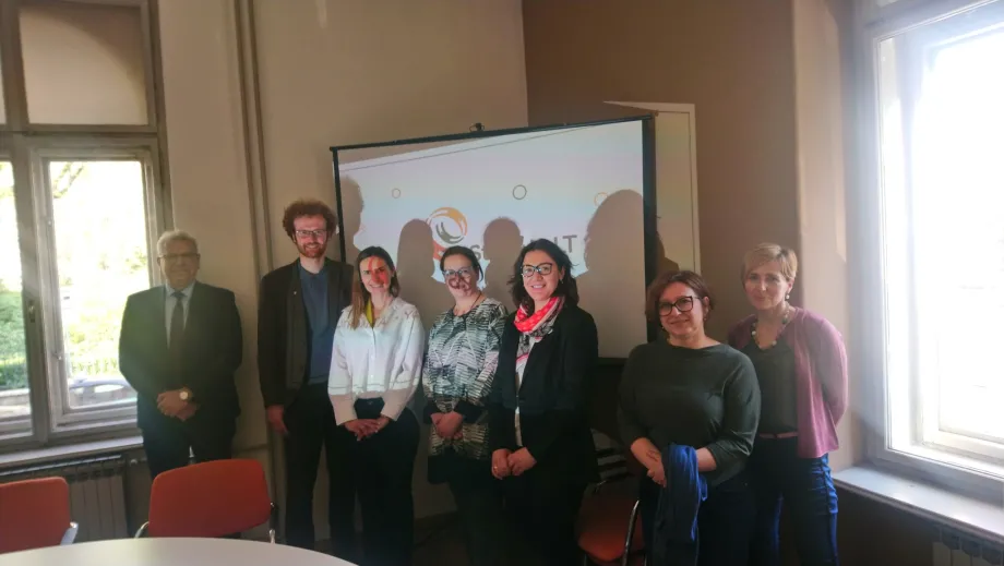 Grupa žena i muškaraca pozira za fotografiju ispred prezentacijskog platna