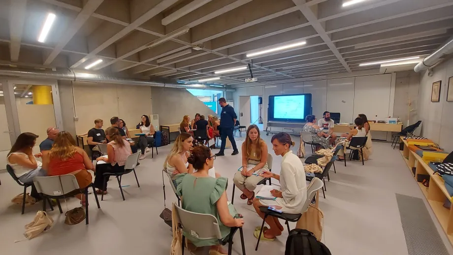 Sudionici treninga sjede za stolovima u grupama