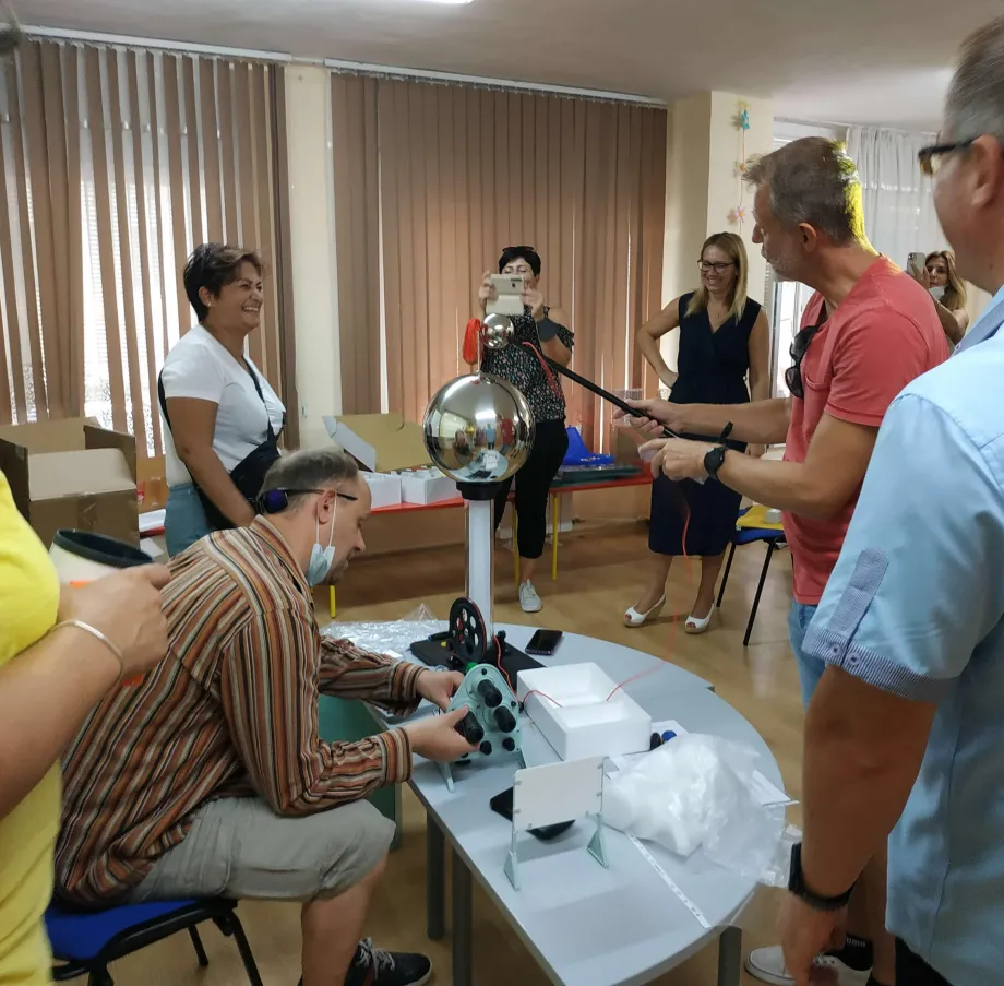 Grupa odraslih provodi eksperiment sa Van de Graaffovim generatorom