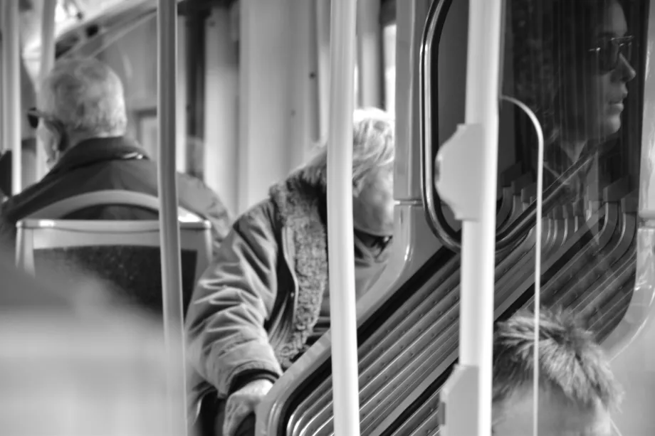 stara gospođa sjedi u busu s pogledom usmjerenim prema van te odraz mlade djevojke s pogledom usmjeren prema van