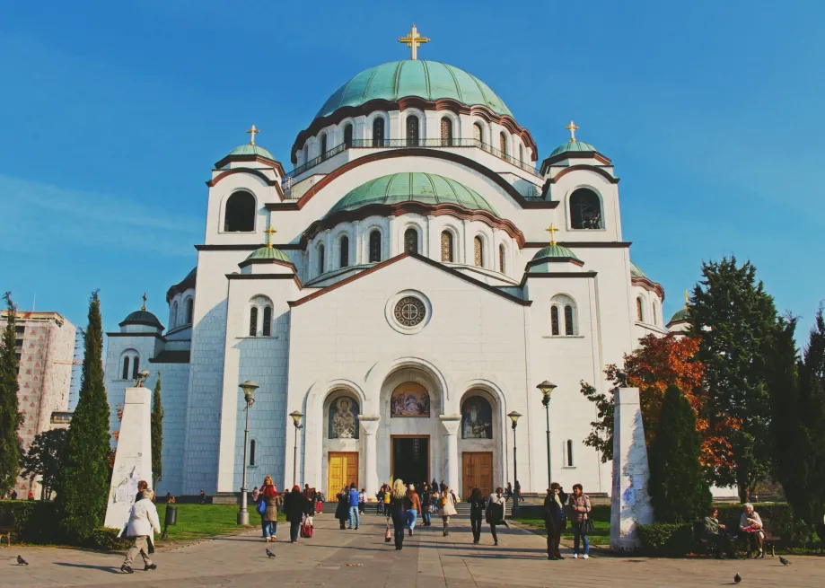 Hram svetog Save u Beogradu okružen drvećem, ljudi šetaju ispred hrama i hodaju prema ulazu u hram