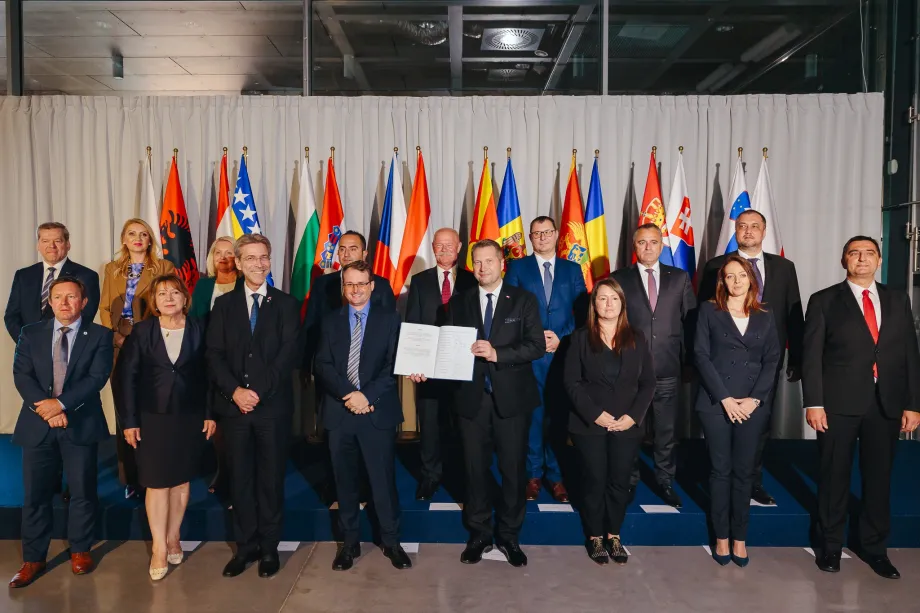Grupa ljudi pozira ispred zastava europskih zemalja za zajedničku fotografiju.