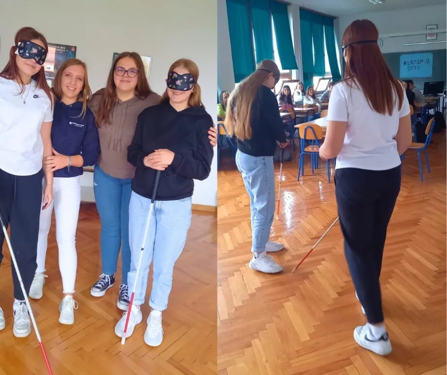 Dvije učenice sa povezima na očima i sklopivim štapovima za slijepe i slabovidne osobe te dvije učenice koje ih vode u učionici.