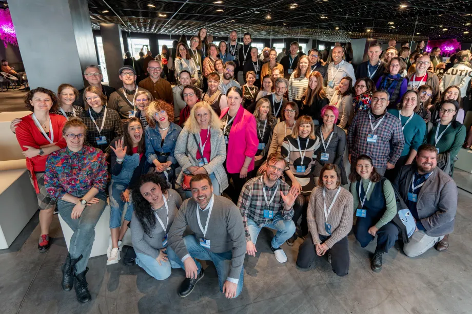 Pedesetak ljudi na konferenciji čuči u prvim redovima i stoji u onim stražnjima i pozira za fotografiju.