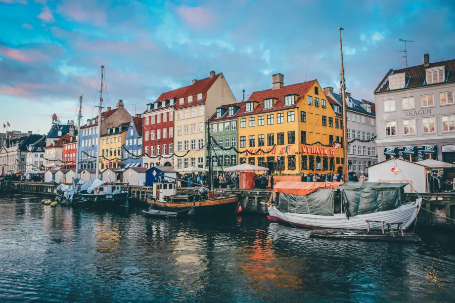 Kopenhagen. Šarena pročelja zgrada uz morski kanal plijene pažnju i daju do znanja da se radi o gradu na Baltiku. Ispred zgrada, uz šetnicu, u moru su privezane tri turističke i ribarske brodice.