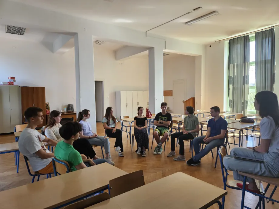 Desetero mladih srednjoškolske dobi sjedi u krugu u učionici.
