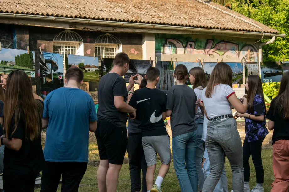 Skupina od desetak djece koja promatra izložene fotografije.