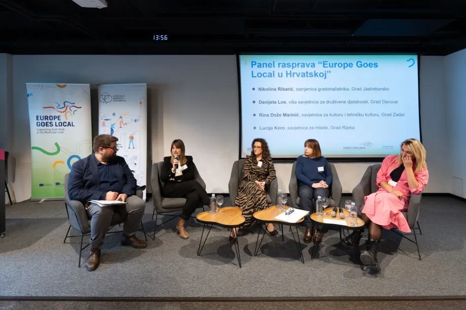 Četiri žene i jedan muškarac sjede i sudjeluju u panel raspravi
