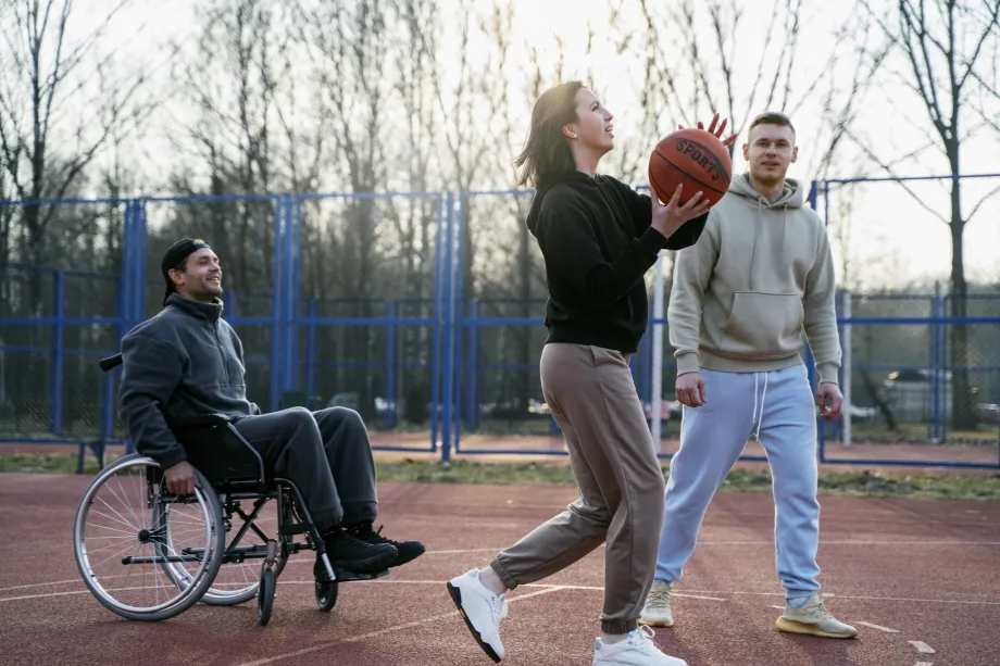 Tri mlade osobe igraju košarku, djevojka drži košarkašku loptu u rukama