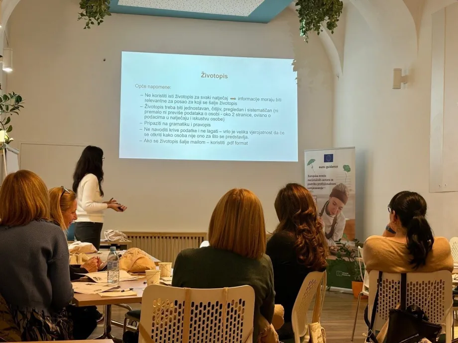 Skupina osoba sluša predavanje ženske osobe na temu životopisa, a informacije su vidljive na projekcijskom platnu