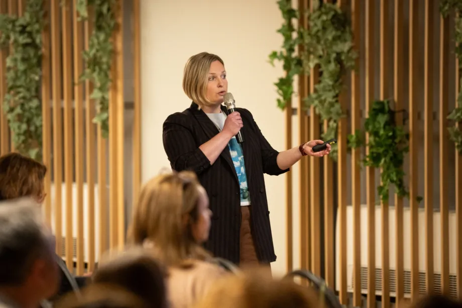 Ženska osoba s mikrofonom i pointerom drži predavanje