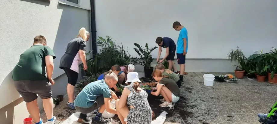 Devetero učenika i jedna učiteljica sade cvijeće u lončanice
